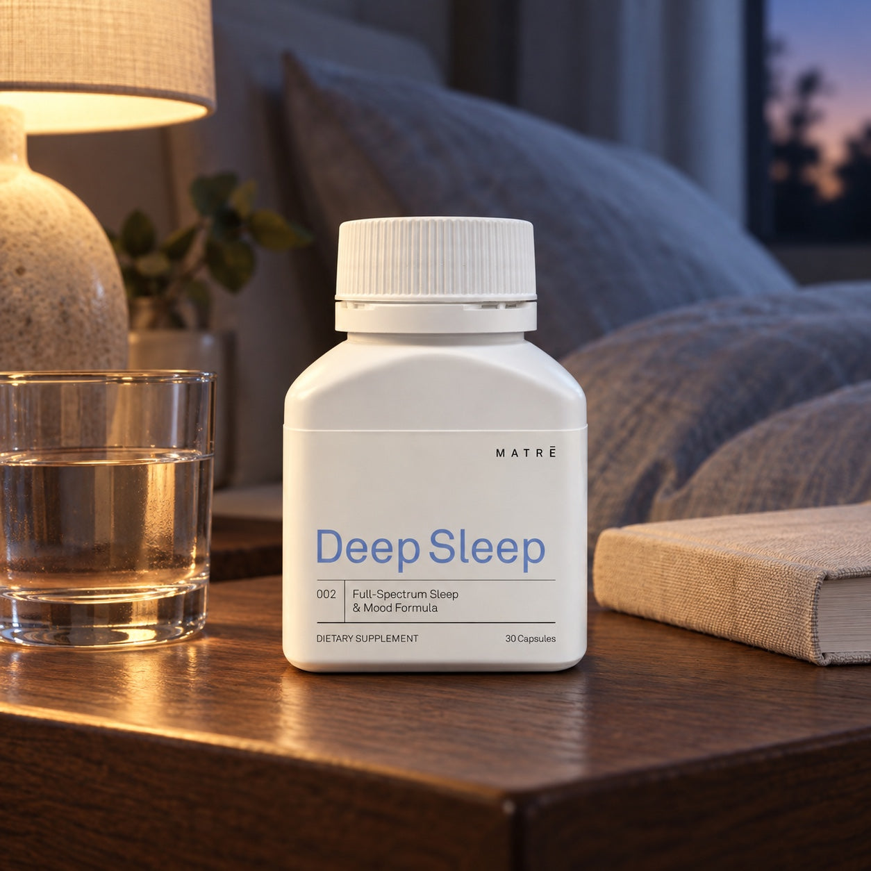 Deep Sleep beside a glass of water on a walnut bedside table